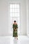 Vertical portrait of a girl in a white studio against the background of a huge window