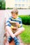 Vertical portrait. Happy boy in the school yard sits on the steps. Adorable little kid boy with books and backpack. Child outdoors