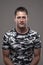 Vertical portrait of happy young relaxed adult man smiling at camera in camouflage army t-shirt