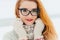 Vertical portrait of the lovely red head woman with glasses softly smiling during the snowfall.