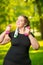 Vertical portrait oversize woman in headphones with dumbbells in hand is engaged in sports