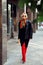 Vertical portrait posh, elegant, fashionable blond woman in sunglasses, black jacket and high heels walking the street