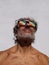 Vertical portrait of a shirtless middle-aged man with colorful perforated glasses looking at the sun