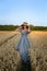 Vertical portrait of a young pretty woman-coquette against the background of a wheat field