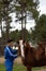 Vertical portrait of a young rancher and farmer guy caring for and petting his horses on his farm