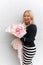 Vertical positive, toothy smiling mature blond woman in black white striped dress hold amazing craft pink rose bouquet