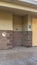 Vertical Public restroom at a golf course with white doors and concerete and brick wall