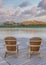 Vertical Puffy clouds at sunset Four wooden lounge chairs facing the reflective Oquirrh Lake at