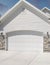 Vertical Puffy clouds at sunset Three car garage exterior with two white garage doors with arche