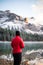 Vertical rear view of a woman in a red jacket enjoying the view of the Louise Alberta Lake, Canada