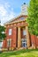 Vertical red brick courthouse with clock tower with blue sky and green tree