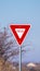 Vertical Red traffic Yield sign alongside a road