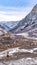 Vertical Road curving amid towering mountain with slopes covered in fresh snow