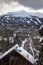 Vertical of rooftops of houses and trees covered with snow with the background of snowy mountains