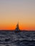 Vertical sailboat in the Adriatic sea on yellow and orange sunset sky background