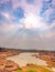 vertical scene of wonderfull sunlight of sun and cloud on sky above small lake surrounding with stone on mountain