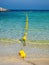 Vertical seascape with floating buoys and rope dividing area on beach. Sea coast on sunny day. Selective focus