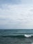 Vertical seascape view with a wavy water surface under a cloudy sky