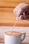 Vertical selective focus shot of a person putting a stick in a cup of coffee