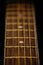 Vertical selective focus shot of strings and fretboard of acoustic guitar