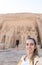 Vertical selfie viewof young beautiful smiling tourist woman with Abu simbel temple in the background