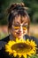 Vertical shallow focus view of a caucasian woman smiling down at a sunflower