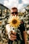 Vertical shallow focused shot of a man holding a yellow sunflower