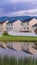 Vertical Shiny pond and pathway amid a grassy terrain in front of homes with balconies