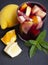 Vertical shoot of a glass with sangria next to a lemon, orange, and mint leaf on black slate base. Typical Spanish drink.