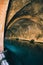 Vertical shot of an abandoned arched tunnel filled with azure water