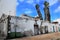 Vertical shot of an aged street wall with green trash under a blue sky with clouds