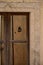 Vertical shot of an antique Sardinian wooden door with rusty decorative iron and knocker