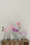 Vertical shot of assorted colorful flowers in individual vases on a wooden table