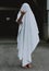 Vertical shot of a barefoot person wearing white ghost sheet showing shaka sign