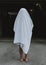 Vertical shot of a barefoot person wearing white ghost sheet.Spooky concept