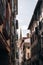 Vertical shot of Bayonne Cathedral at a distance seen behind buildings on narrow alley