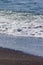 Vertical shot of a beach during the daytime with the waves washing up to the sandy shoreline