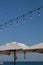 Vertical shot of beach parasols with light bulbs hanging above on a cloudless day