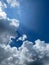 Vertical shot of a a beautiful bright blue sky with rainstorm clouds and sunbeams.