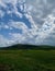 Vertical shot of a beautiful grassy landscape surrounded by mountains under a cloudy sky