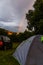 Vertical shot of the beautiful rainbow shining in the gloomy sky behind a tent and a car