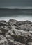 Vertical shot of the beautiful rocks on the beach with the foggy ocean in the background