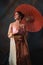 Vertical shot of a beautiful Southeast Asian woman in a traditional Thai dress with an umbrella