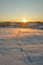 Vertical shot of a beautiful sunrise on a mountain field covered by snow an footsteps