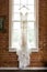 Vertical shot of beautiful white wedding drees hung near the window