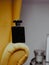 Vertical shot of a black aesthetic perfume bottle on yellow furniture