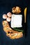 Vertical shot of a block of cheese, dried gourmet bread pieces, and walnuts on a black table