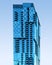 Vertical shot of a blue glass skyscraper under the clear blue sky