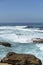 Vertical shot of the blue sea and a rocky shore