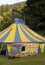 Vertical shot of a blue and yellow carnival tent with a circus truck